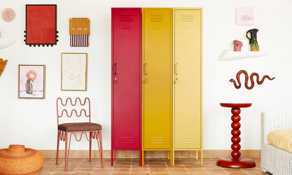 The Skinny lockers in Poppy, Mustard and Butter lined up against a gallery wall with a wavy chair and side table