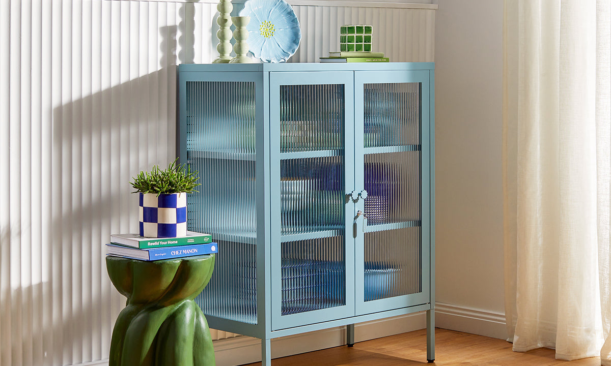 Mustard Made's The Mixer glass cabinet in Ocean, a pale dusty blue, styled with ceramics against fluted wall panelling