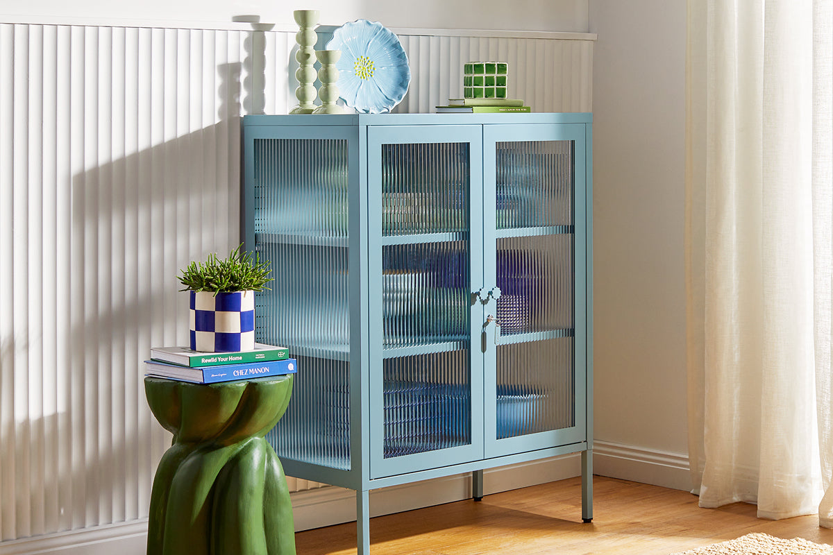Mustard Made's The Mixer glass cabinet in Ocean, a pale dusty blue, styled with ceramics against fluted wall panelling