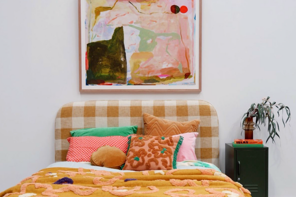Colourful artwork hanging above a bed, a Mustard Made locker is beside the bed.