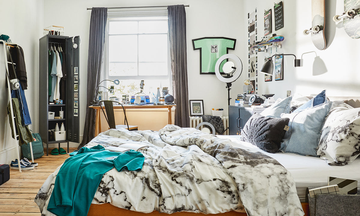 The Skinny locker in Slate, open as a wardrobe in a student halls room with a desk by the window and skateboards on the wall