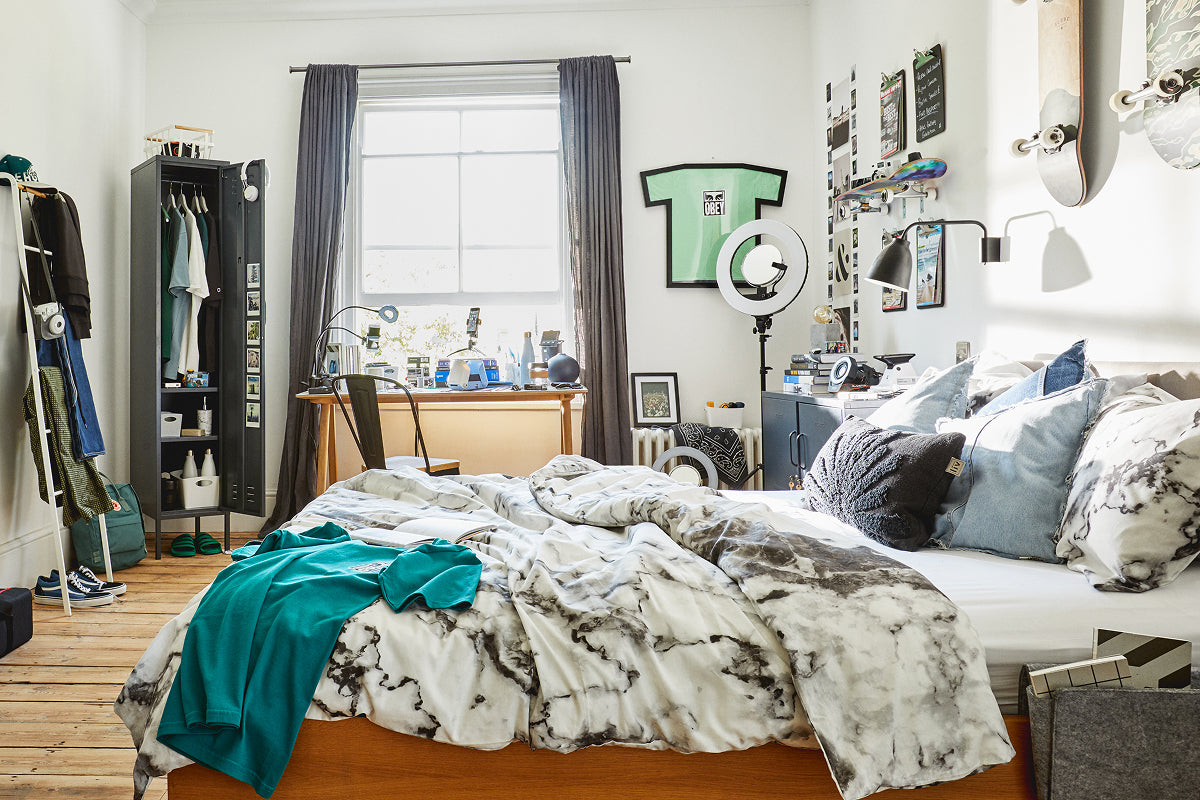 The Skinny locker in Slate, open as a wardrobe in a student halls room with a desk by the window and skateboards on the wall