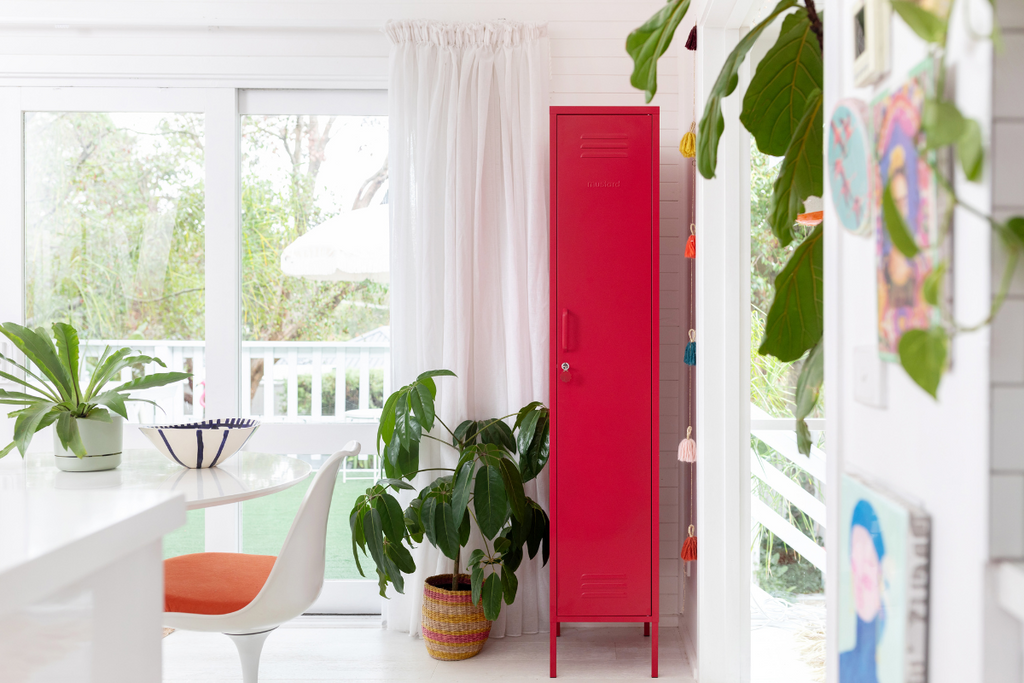 A Skinny locker in Poppy stands out in a white, airy room filled with plants and natural light.