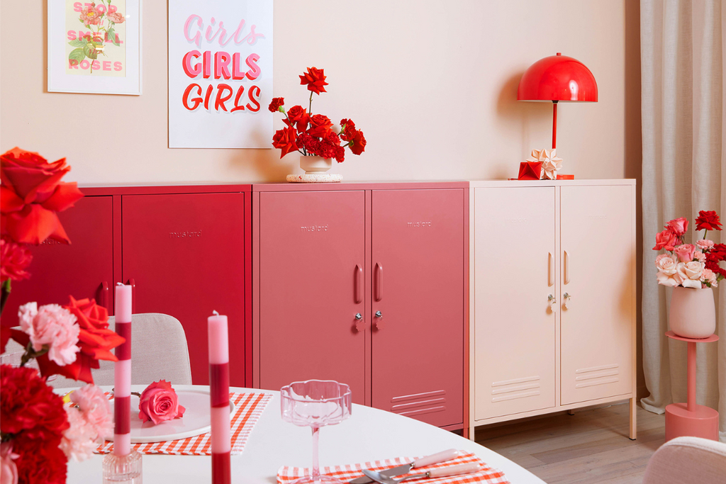 A trio of Mustard Made Midi lockers in an ombre pattern ranging from red to blush pink. The space is filled with red and pink accessories and artworks.